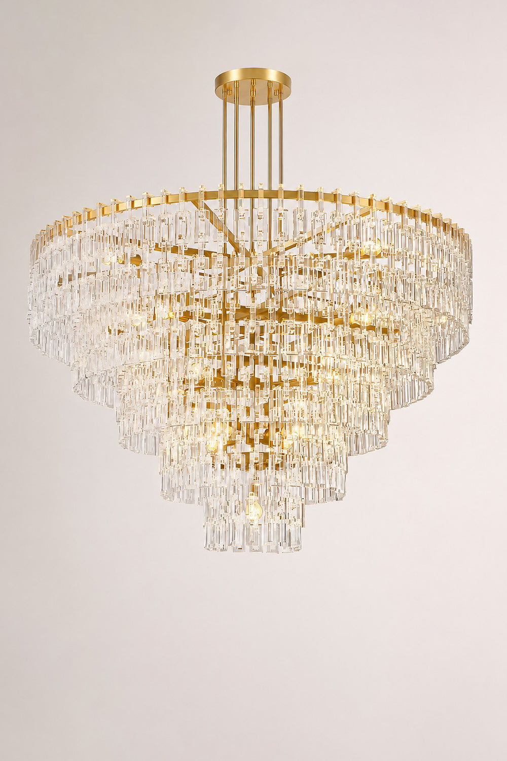 Aven Tiered Glass Prism Chandelier | Glass, Metal | Studio mockup shot of the fully lit gold brass tiered crystal chandelier radiating a rich ambient glow on a grey background | vexa lamps