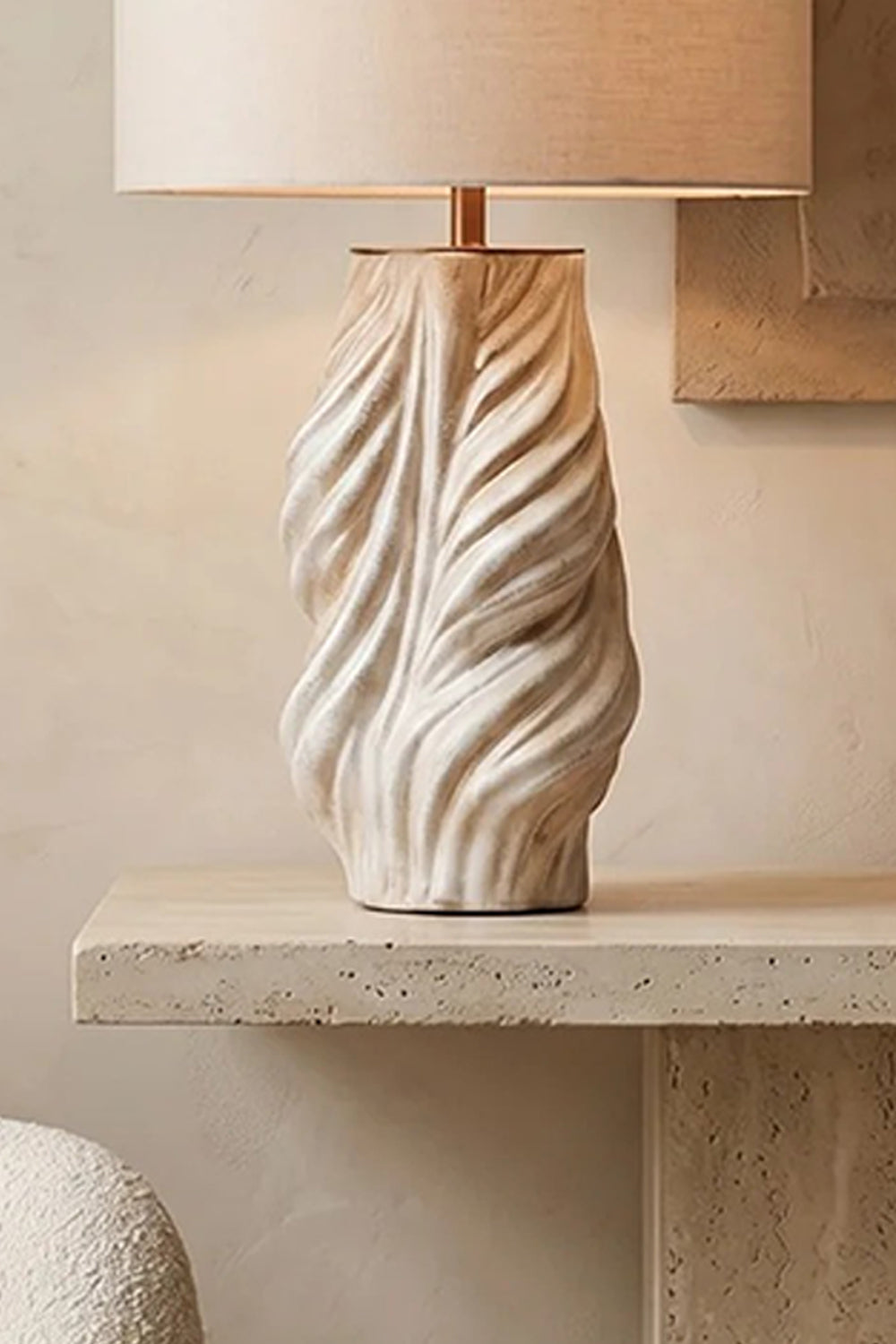 Adara Sculptural Ceramic Table Lamp | Ceramic, Fabric | Close-up side view showcasing the organic, deeply carved wavy ridges of the cream sculptural ceramic base resting on stone | Detail shot | vexa lamps