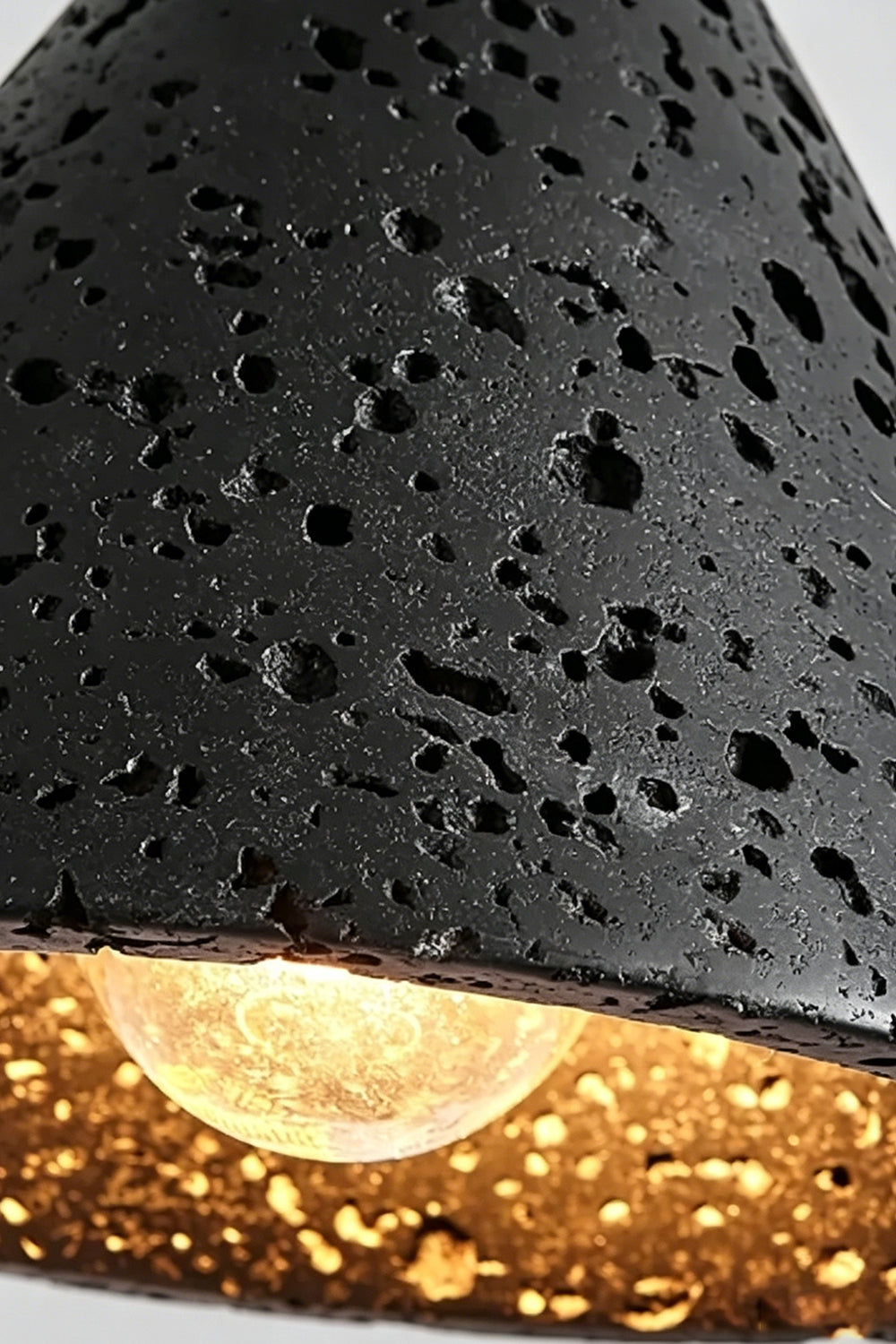 Aethel Core Detail Shot | Black Travertine, Metal | Close-up of porous texture and lit bulb | vexa lamps