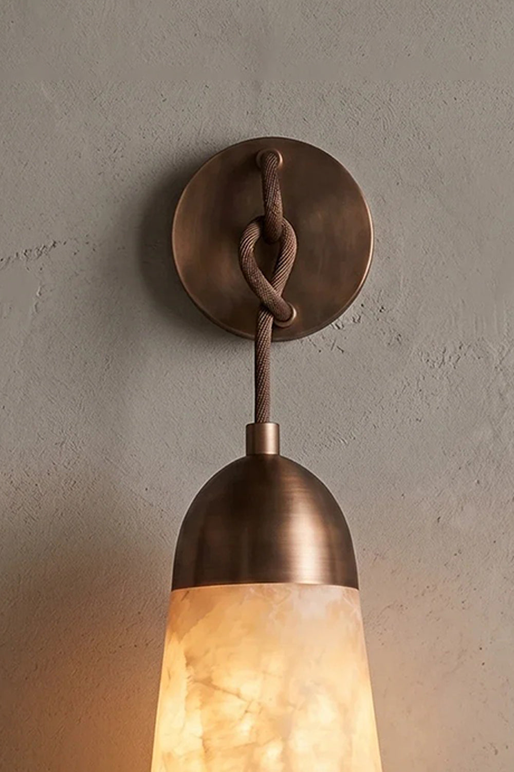 Alabaster Teardrop Wall Sconce showcasing natural alabaster stone and knotted cord design on textured wall.