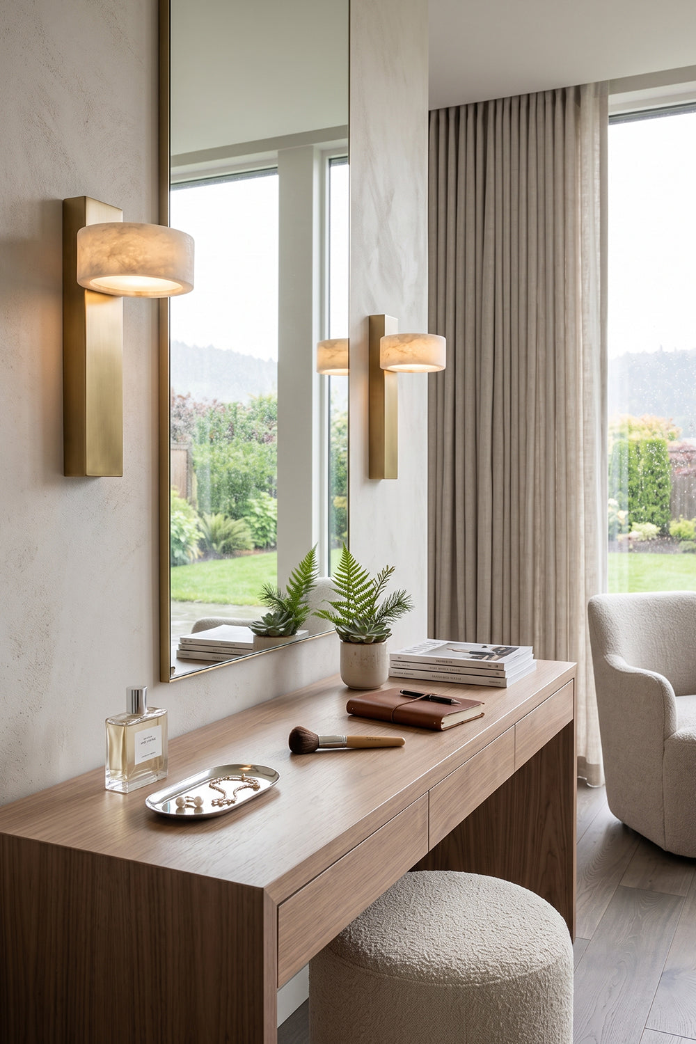 Alaric Alabaster Bar Wall Sconce | Natural Alabaster and Brass | Installed on a wall panel next to a large mirror in an elegant vanity makeup area with a stool | vexa lamps