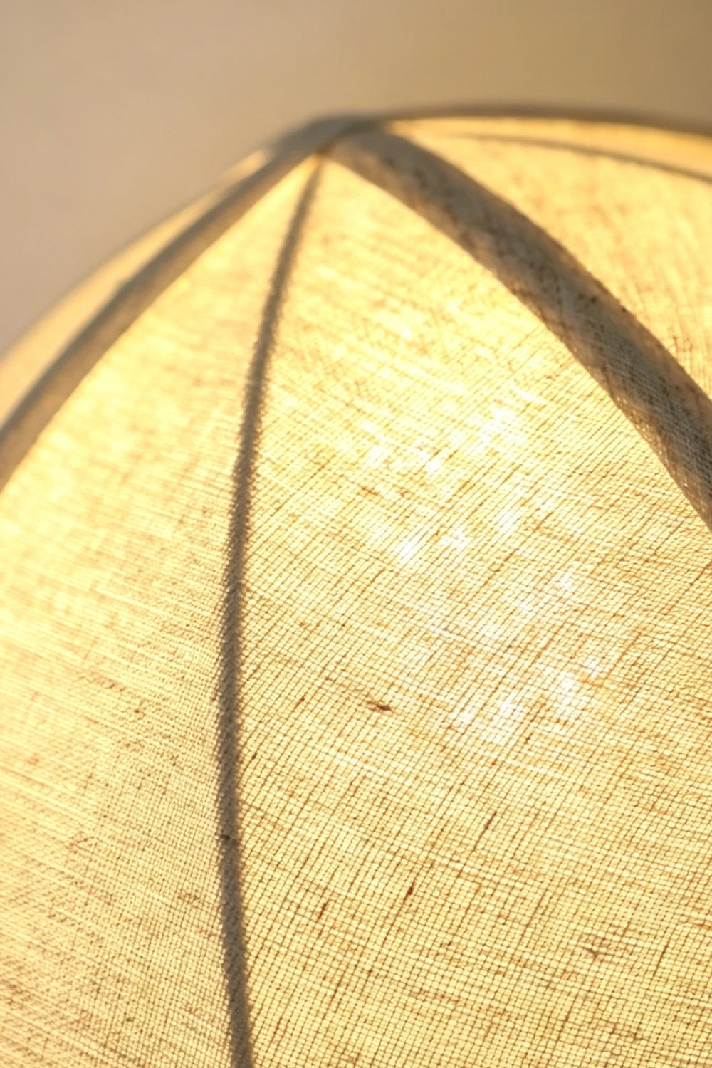 Angolo Canted Faceted Wood Table Lamp | Wood, Fabric, Metal | Macro close-up of the lit fabric lampshade, highlighting the ribbed panels and textured material | Detail shot | vexa lamps