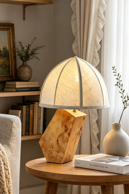 Angolo Canted Faceted Wood Table Lamp | Wood, Fabric, Metal | Sitting on a round wooden end table next to a sofa and airy curtains, casting soft ambient light | vexa lamps