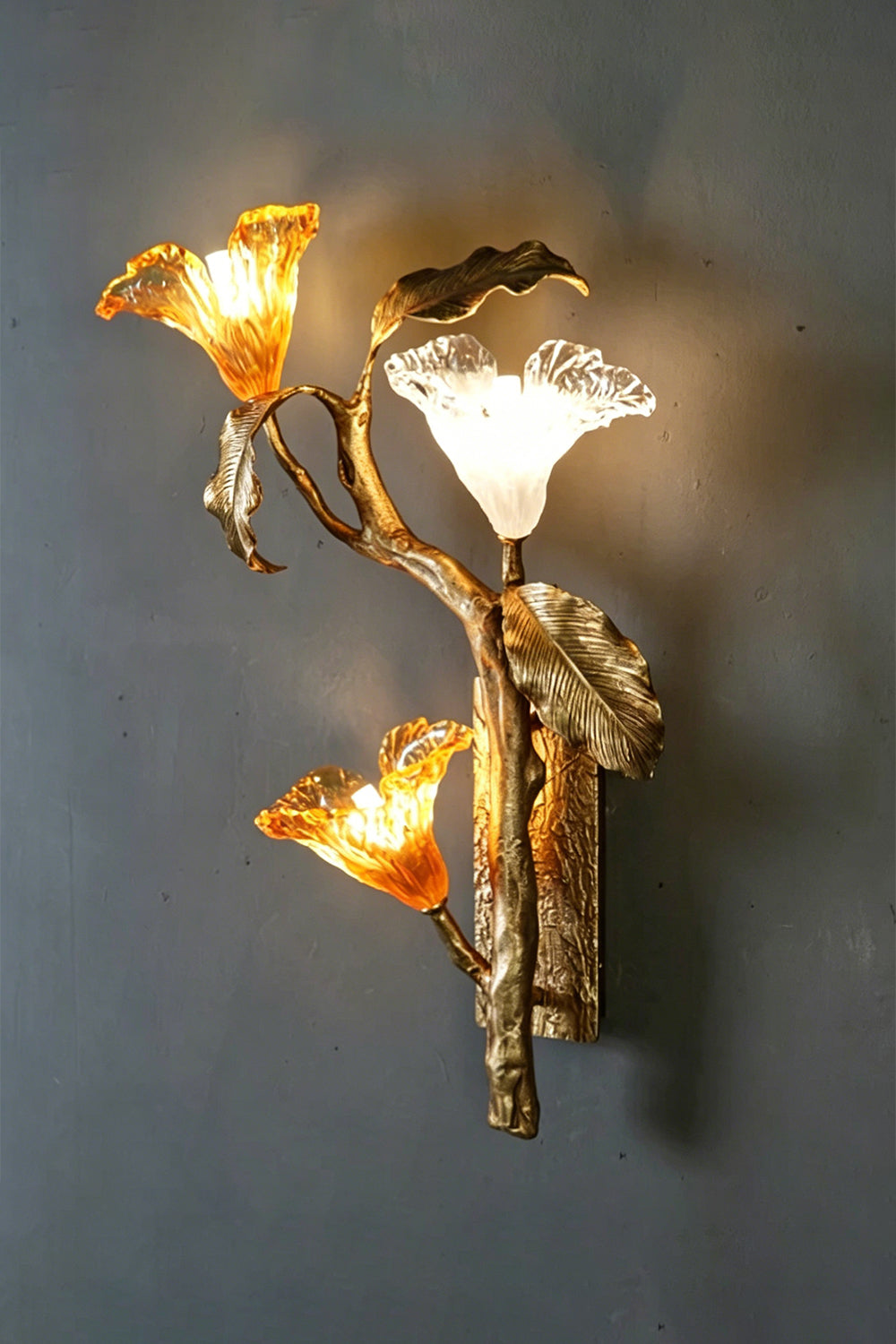Arboreal Bloom Brass Wall Lamp | Brass, Glass | Frontal view of the fully lit lamp against a grey textured wall | Isolated shot | vexa lamps