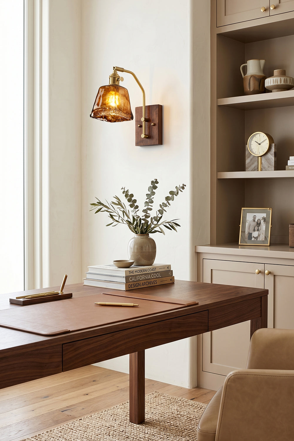 Arlo Amber Ripple Wall Lamp | Glass, Metal, Wood | Providing a warm ambient glow over a dark wood desk workspace in a traditional home library with built-in shelves | vexa lamps