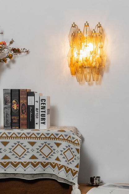 Lit amber polyhedral glass wall lamp | Metal, Glass | Mounted on a white wall above a console with books | vexa lamps