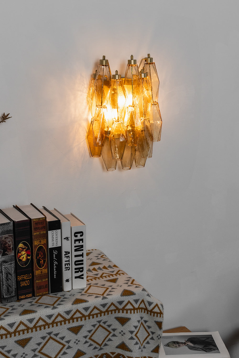 Lit amber Art Poliedri wall sconce | Metal, Glass | Centered on a white wall above a wooden cabinet | vexa lamps