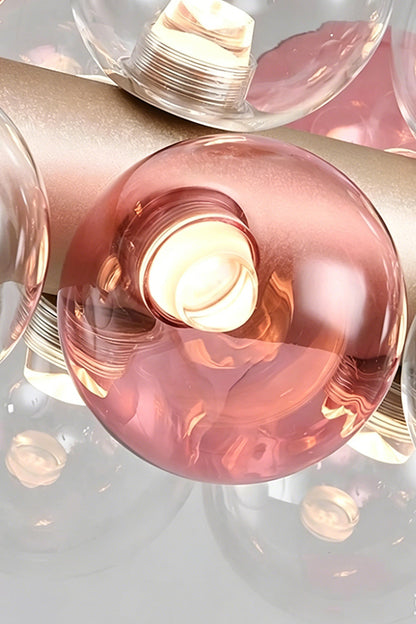 Astraea Linear Prismatic Globe Chandelier showcasing stylish hand-blown glass spheres with pink accents and a brushed gold finish.