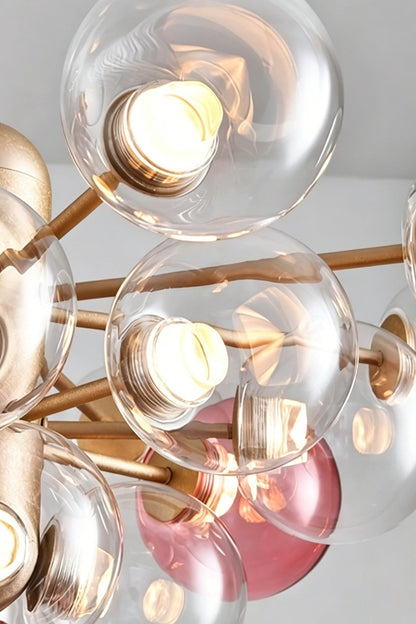 Astraea Prismatic Globe Chandelier | Glass, Metal | Close-up focus on the illuminated clear and pink glass sphere globes showcasing the light transmission and bubble cluster effect | Detail shot | vexa lamps