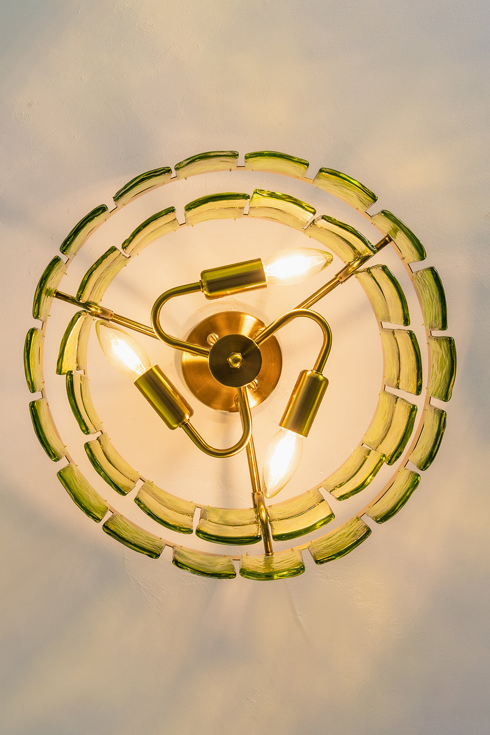 Aura Verdant Tiered Green Glass Ceiling Light | Metal, Glass | Looking directly up at the illuminated ceiling light, showing the symmetrical three-bulb structure | Detail shot | vexa lamps