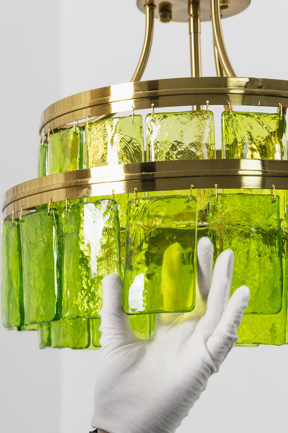 Aura Verdant Tiered Green Glass Ceiling Light | Metal, Glass | A white-gloved hand adjusting the bottom section of the two-tier green glass fixture | Detail shot | vexa lamps