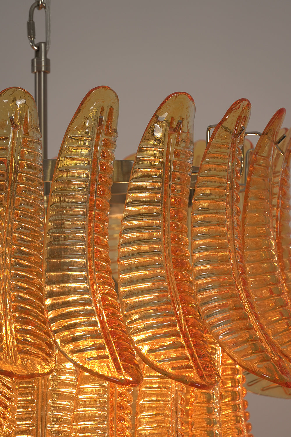 Close-up view of the textured amber glass plumes of the Aurelia Helix Amber Glass Cascade Chandelier.