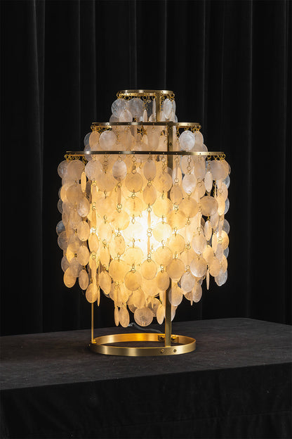 Aurelia Tiered Capiz Table Lamp | Capiz Shell, Metal | Dramatic dark studio shot of the fully illuminated tiered lamp radiating an intense golden glow against a black backdrop | vexa lamps