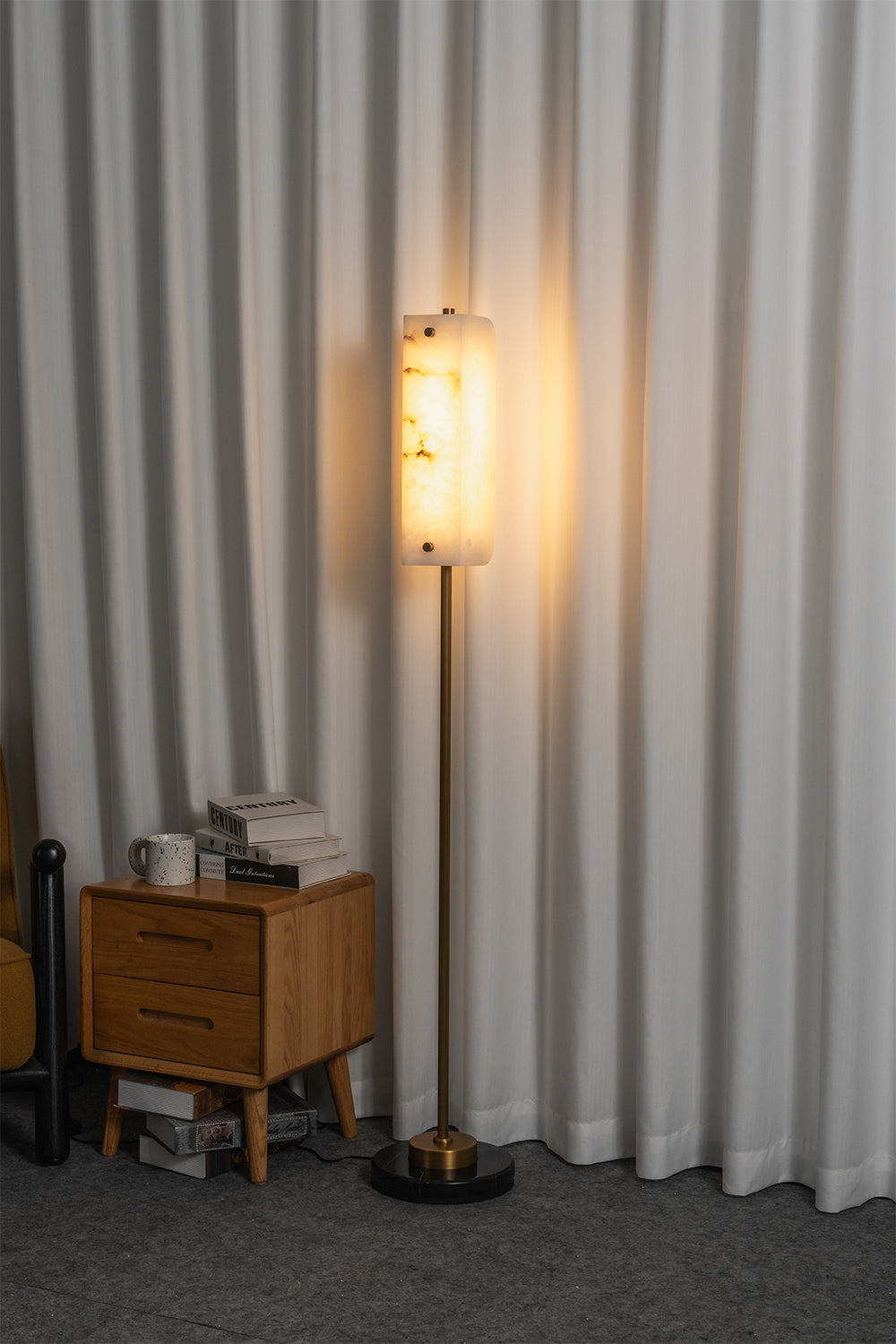 Aurelius Alabaster Brass Floor Lamp | Alabaster, Brass | Fully illuminated linear floor lamp casting a cozy golden ambient glow through the natural stone shade next to a wood side table | vexa lamps