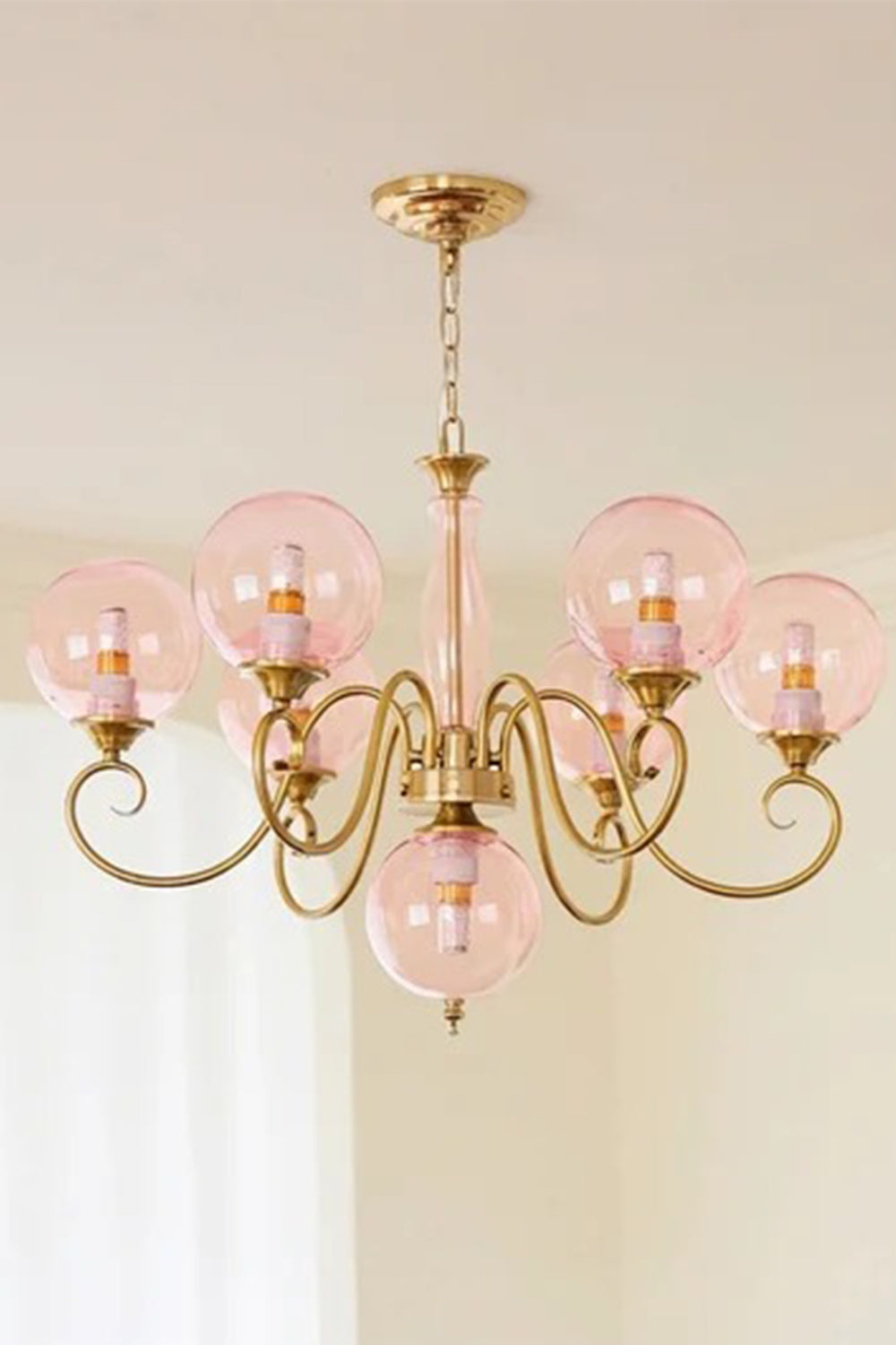 Aveline Globe Cluster Chandelier | Colored Glass and Brass | Front illuminated view displaying pink glass globes against a soft wall | vexa lamps