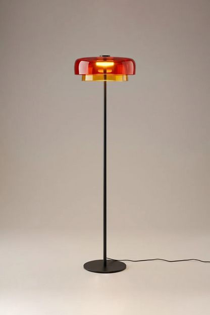 Aven Minimalist Architectural Floor Lamp | Glass, Metal | Studio view of the fully illuminated orange glass variant radiating a cozy sunset hue halo on a neutral studio backdrop | vexa lamps