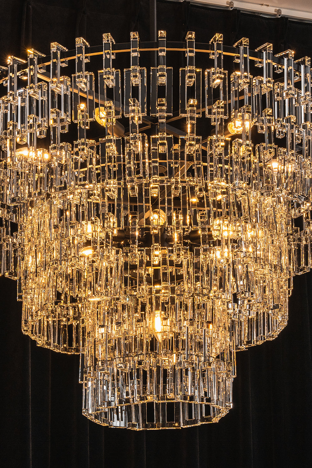 Aven Tiered Glass Prism Chandelier | Glass, Metal | Close-up studio shot of the illuminated chandelier tiers filled with sparkling warm yellow ambient light | vexa lamps