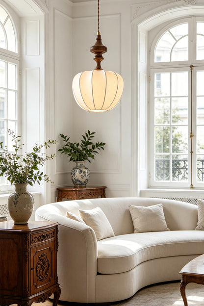 Baird Mid-Century Silk Pendant Light illuminating a stylish living room with a curved sofa and decorative plants.