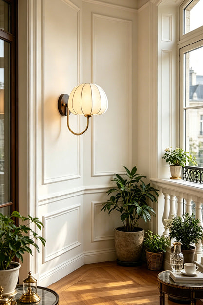 Baird Mid Century Pumpkin Wall Lamp | Metal, Fabric, Wood | Illuminating a bright, sunlit room corner filled with green potted plants near a window | vexa lamps
