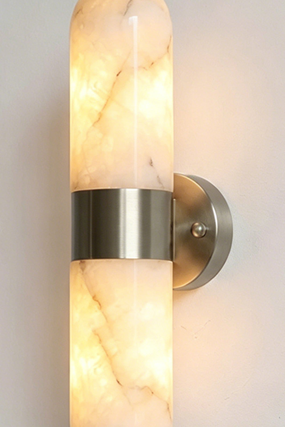 Calla Alabaster Capsule Wall Sconce | Alabaster, Metal | Close-up studio shot of the illuminated capsule wall fixture featuring the silver chrome hardware variant finish | Detail shot | vexa lamps