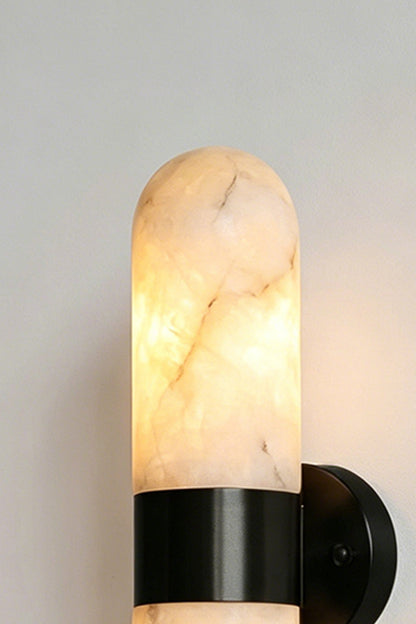 Calla Alabaster Capsule Wall Sconce | Alabaster, Metal | Close-up focus on the rounded dome of the glowing natural stone shade secured by a sleek matte black metal band | Detail shot | vexa lamps