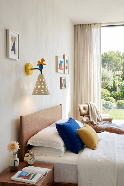 Carousel Horizon Ceramic Wall Sconce | Metal, Resin, Ceramics | Wall-mounted in a bright kid's bedroom beside a bed with vibrant blue and yellow pillows | vexa lamps Carousel Horizon