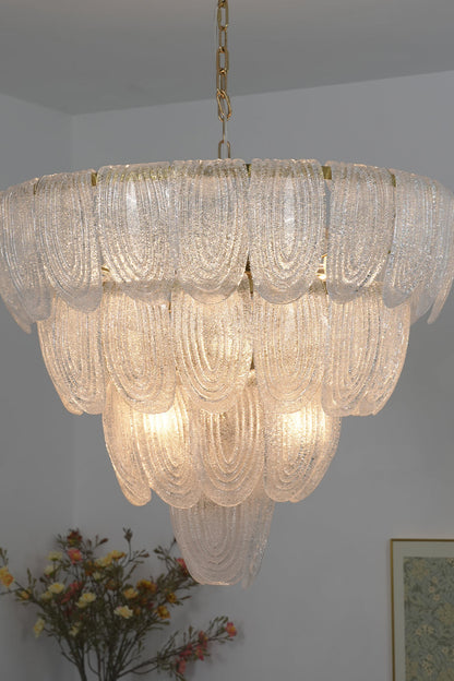 Lit cascading glass chandelier against neutral wall | Metal, Glass | Side perspective showing the tiered petal arrangement | vexa lamps