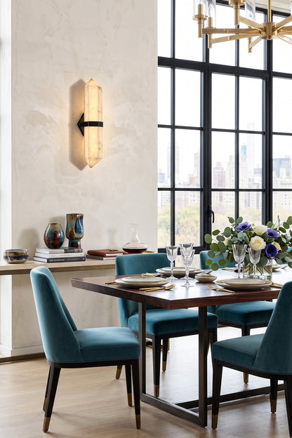 Cassian Faceted Alabaster Wall Sconce illuminating a dining area with modern furniture and a scenic view.