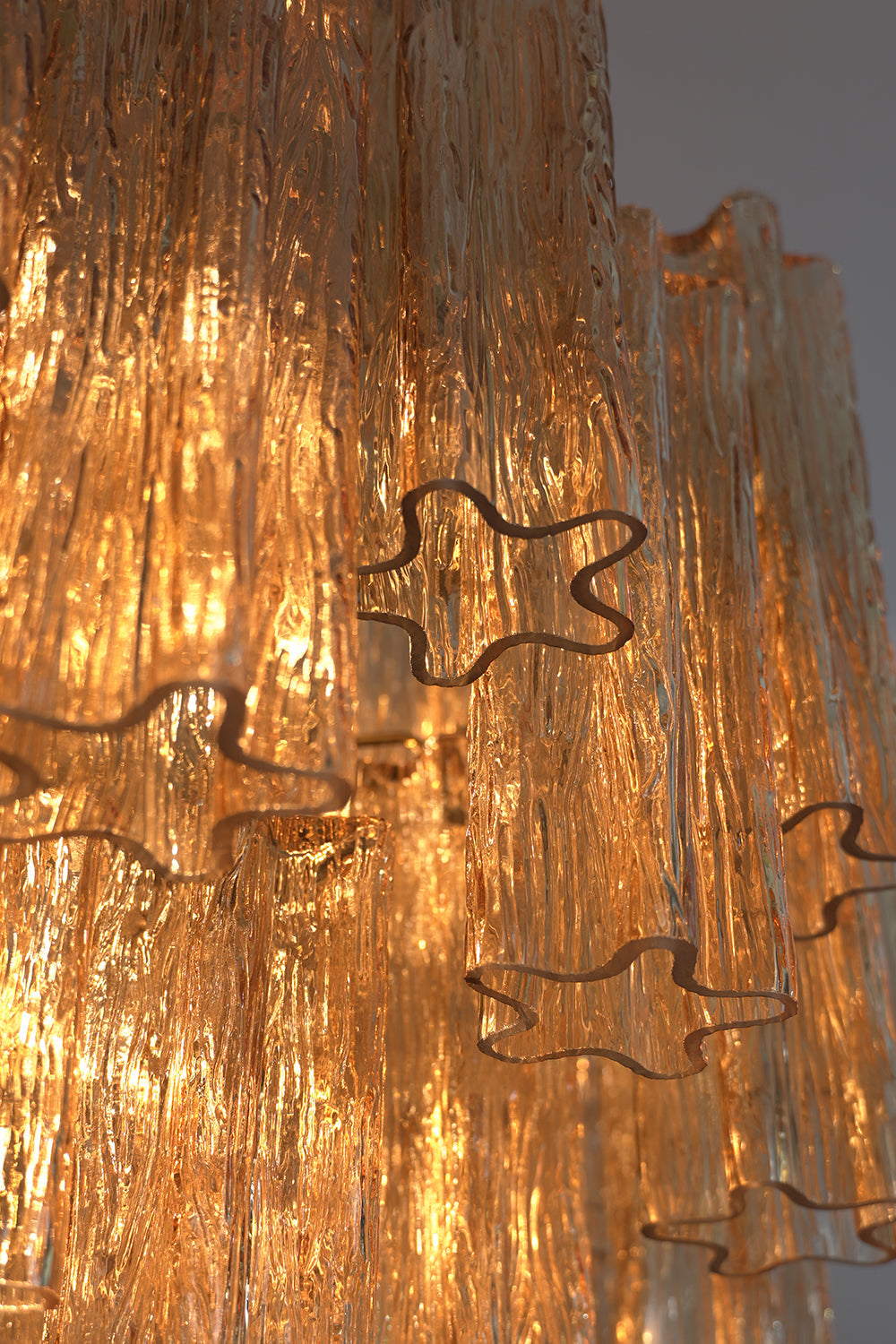 Illuminated detail of the Celestial Glass Cascade Chandelier showcasing fluted glass tubes and light reflections.