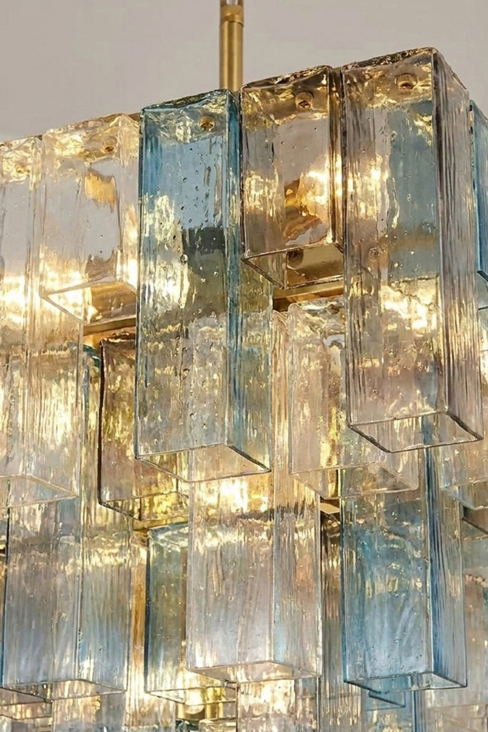 Clarissa Tiered Square Glass Chandelier | Textured Glass Detail | Close-up illuminated shot focusing on the refractive light filtering through the layered blue and clear textured glass plates | Detail shot | vexa lamps