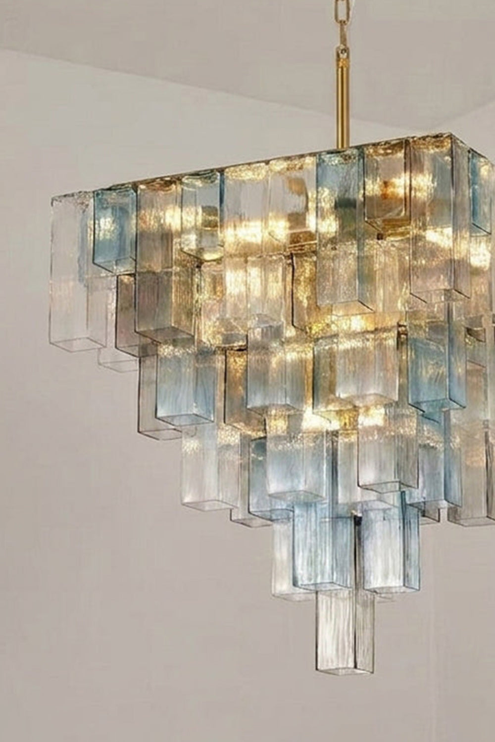 Clarissa Tiered Square Glass Chandelier | Angled Scone View | Architectural close-up view looking up at the illuminated V-shaped tiered square glass chandelier showing its geometric lines | Detail shot | vexa lamps