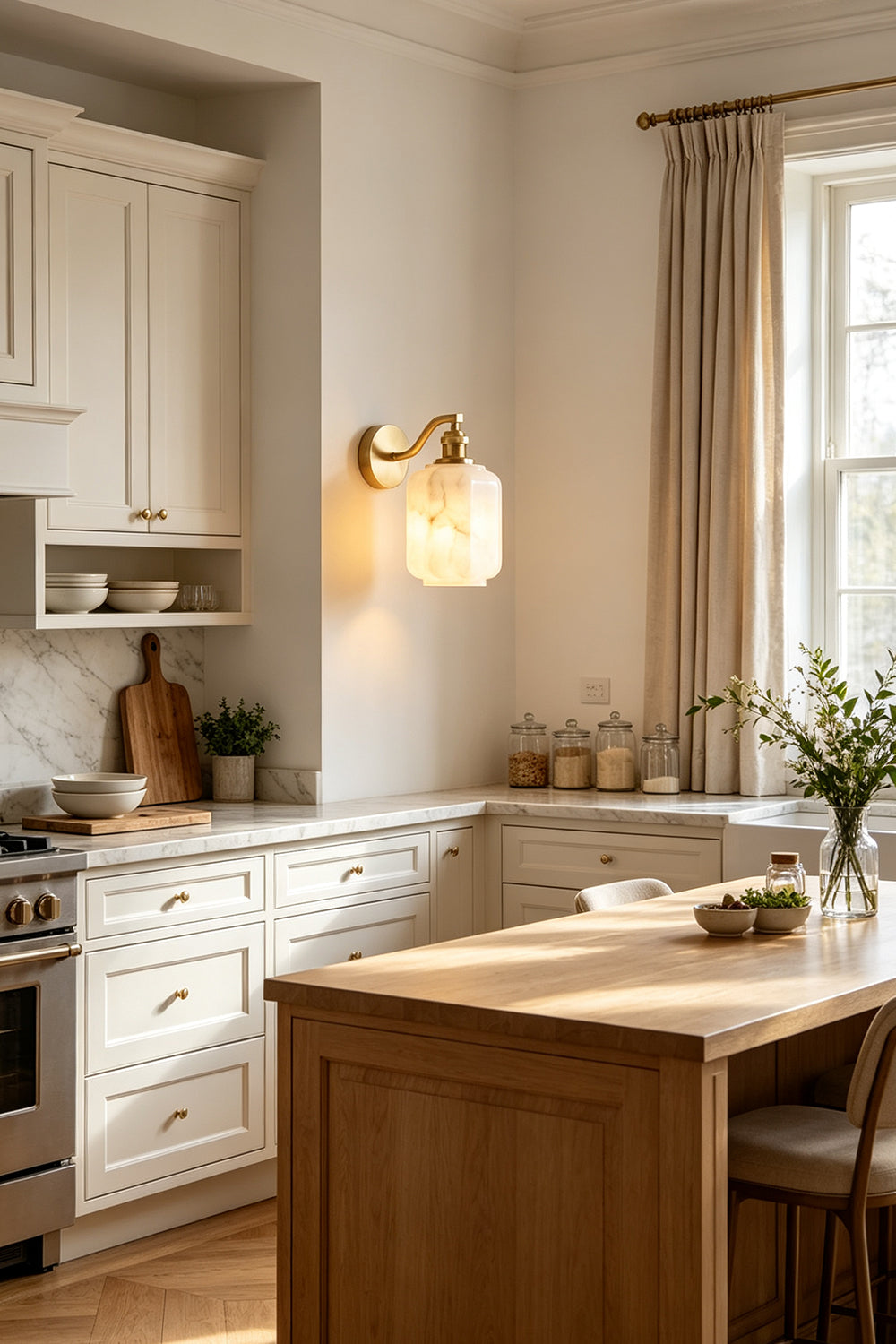Cordelia Scalloped Alabaster Wall Sconce | Natural Alabaster and Brushed Brass | Fixed on a kitchen wall providing ambient illumination above wooden counters and an island | vexa lamps