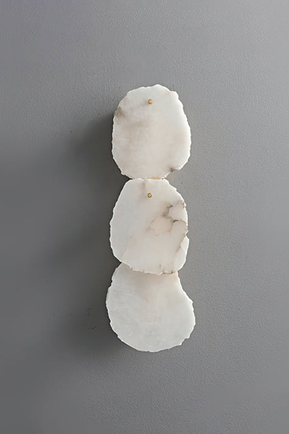 Corin Alabaster Wall Sconce featuring three stacked alabaster pieces with gold accents on a gray wall.