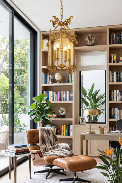 Corwin Glazed Brass Pendant Light illuminating a modern reading nook with bookshelves and a stylish armchair.