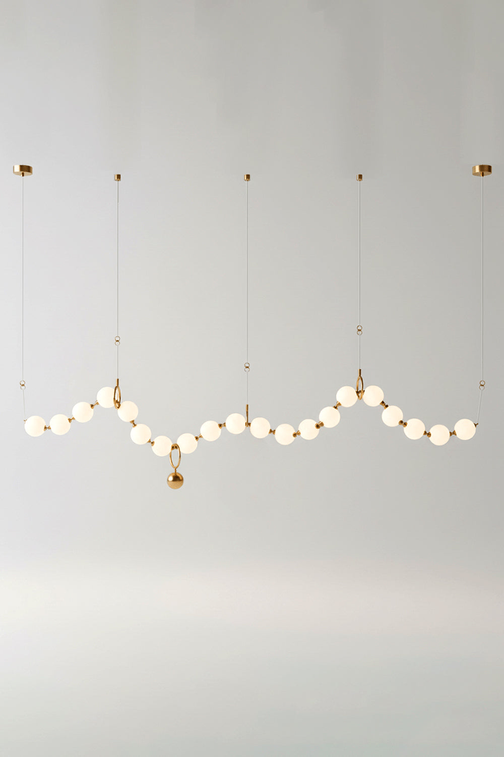 Delphine Pearl Strand Chandelier showcasing matte-white globes in a brass-toned design, perfect for elegant lighting.