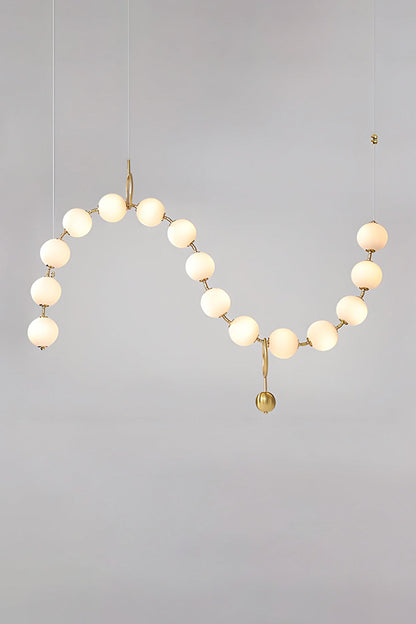 Delphine Pearl Strand Chandelier featuring matte-white globes and brass-toned chain for elegant lighting.