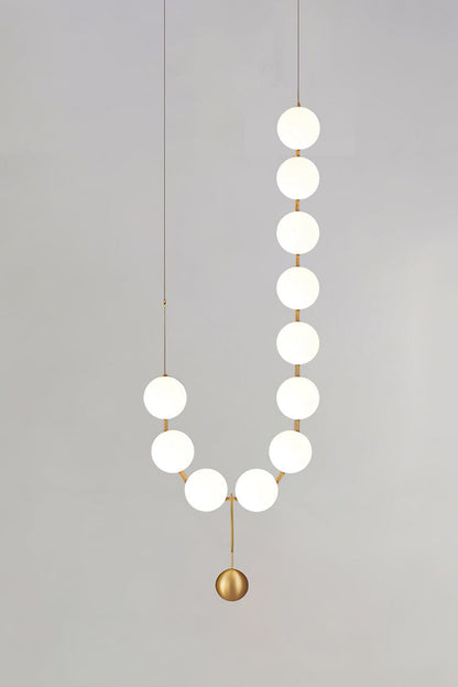 Delphine Pearl Strand Chandelier with matte-white globes and brass-toned details, perfect for elegant lighting.