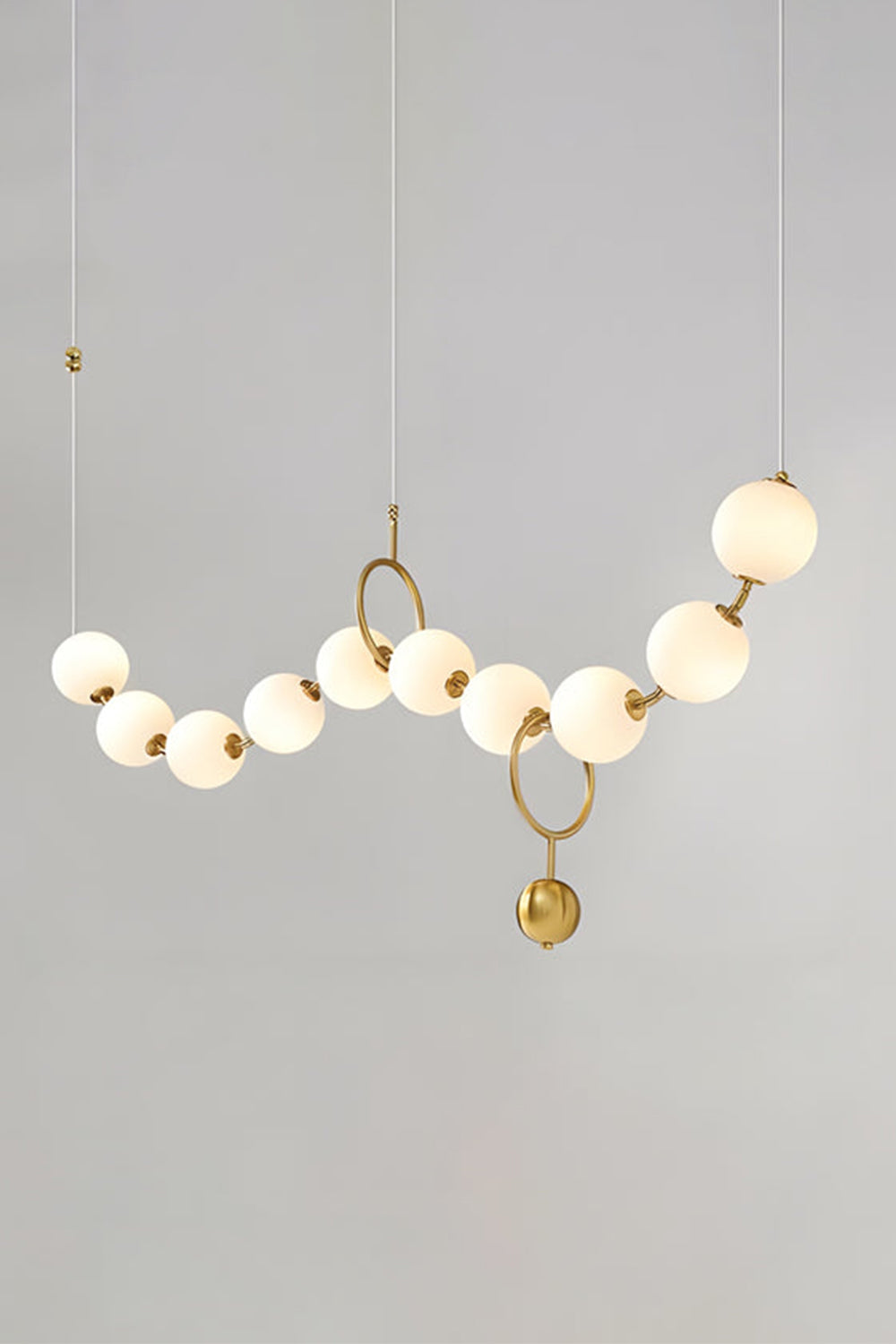 Delphine Pearl Strand Chandelier with matte-white globes and brass accents, perfect for elegant light styling.