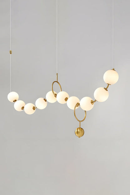 Delphine Pearl Strand Chandelier with matte-white globes and brass accents, perfect for elegant light styling.