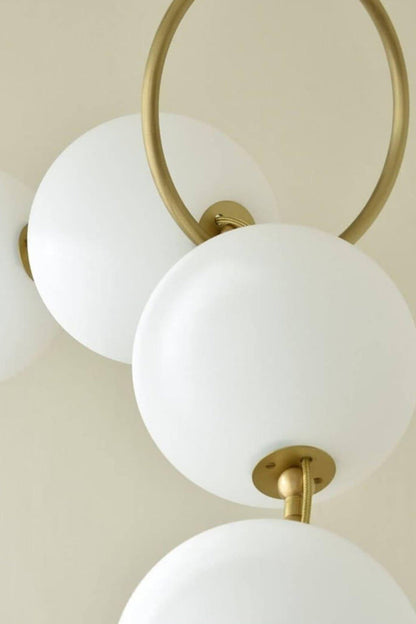 Delphine Pearl Strand Chandelier showcasing matte-white globes with a brass-toned chain detail.
