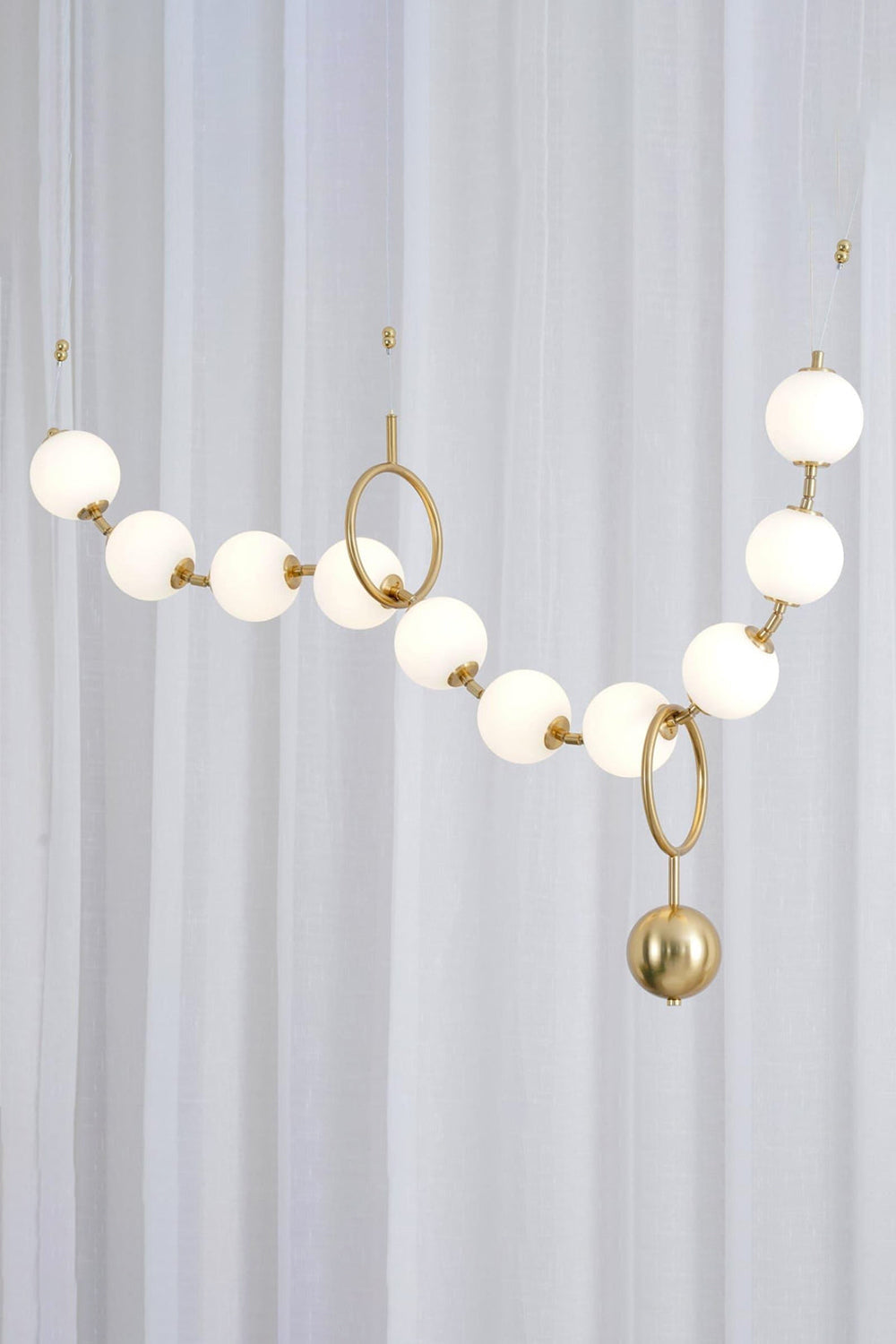 Delphine Pearl Strand Chandelier featuring matte-white globes and a brass-toned chain, ideal for modern interiors.