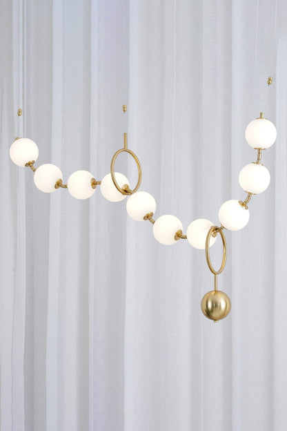Delphine Pearl Strand Chandelier featuring matte-white globes and a brass-toned chain, ideal for modern interiors.