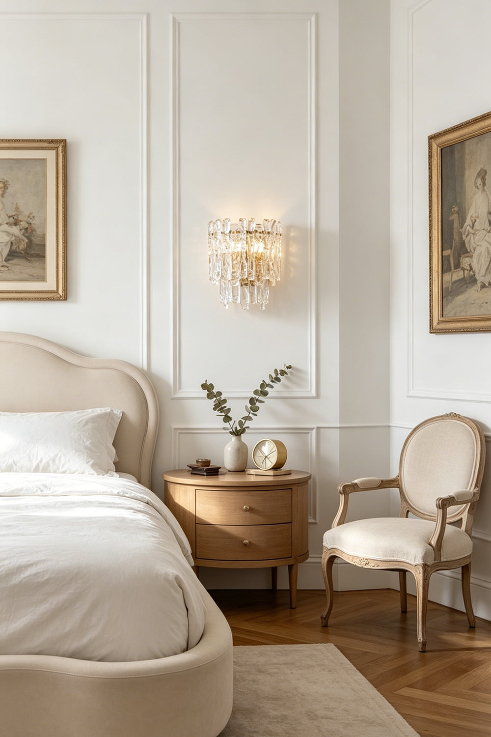 Elara Textured Cast Glass Wall Lamp | Textured Cast Glass, Polished Brass | Installed on a white panelled wall above a formal wooden nightstand with books and a vase, next to an elegant bedroom's four-poster bed frame | vexa lamps