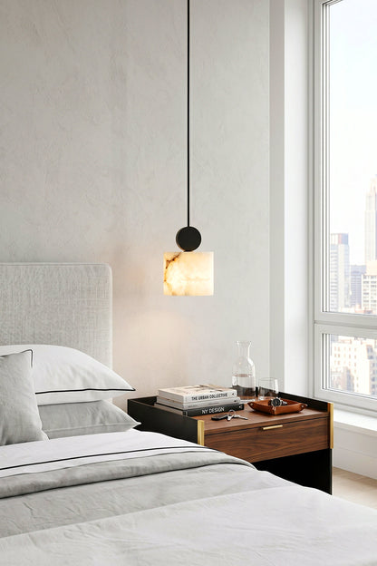 Elian Minimalist Alabaster Pendant Light hanging above a bedside table in a modern bedroom setting.