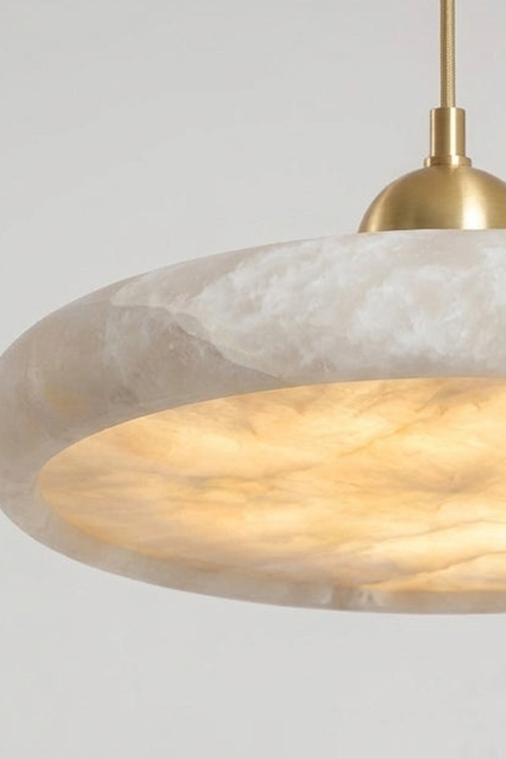 Elowen Alabaster Disc Pendant Light| Natural Alabaster and Brass | Close-up side view highlighting the warm ambient glow radiating from the heavy stone disc fixture | vexa lamps