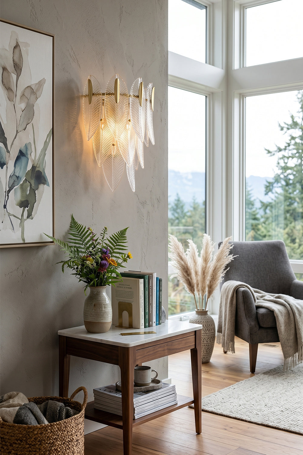 Elowen Cascading Glass Wall Lamp | Glass, Metal | Providing a warm ambient glow on a wall next to a stylish end table with flowers, a grey lounge armchair, and pampas grass | vexa lamps