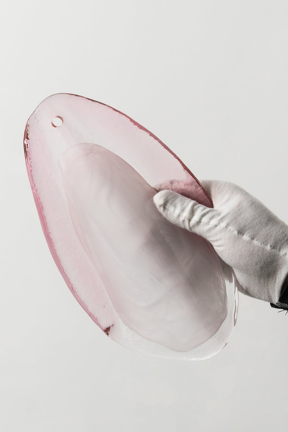 Elysian Bloom Glass Wall Lamp | Metal, Glass | A gloved hand holding a single translucent pink glass petal to show size and texture | Detail shot | vexa lamps