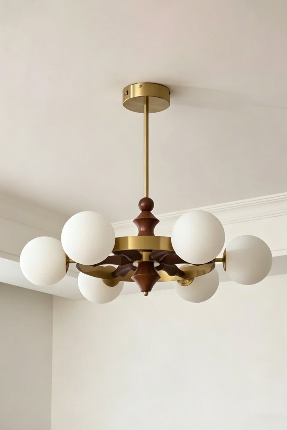 Lit white glass globe version of the Elysian Circlet Chandelier | Metal, Glass, Wood | Perspective view against a neutral wall | vexa lamps