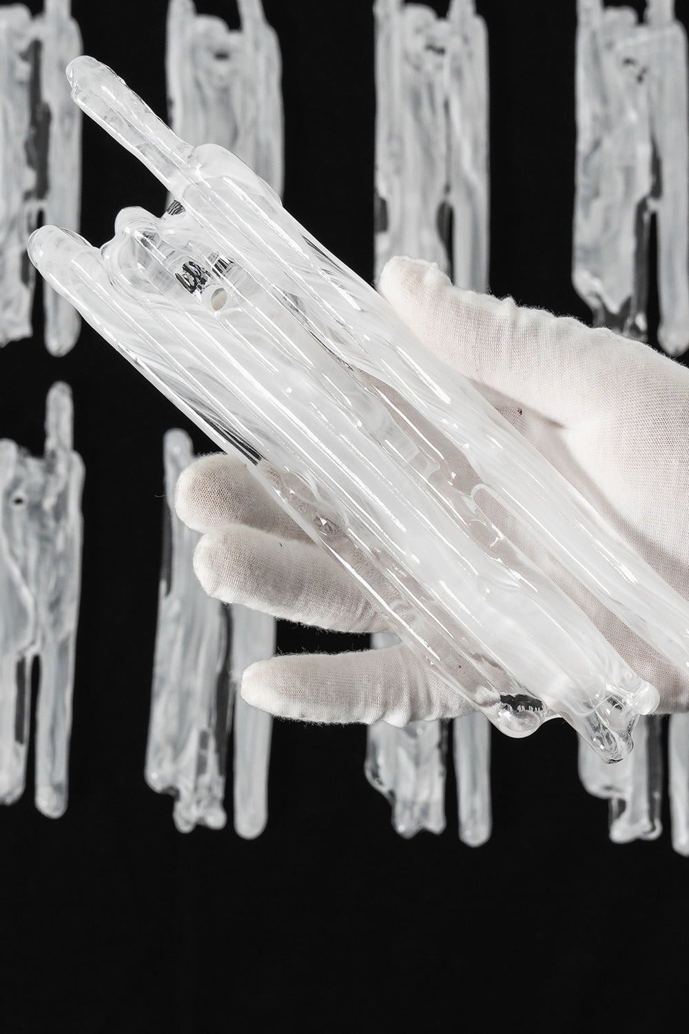 Ethereal Icicle Waterfall Chandelier | Glass, Metal | A gloved hand inspecting a single organic hand-blown glass panel to demonstrate its textured icicle design | Scale reference shot | vexa lamps