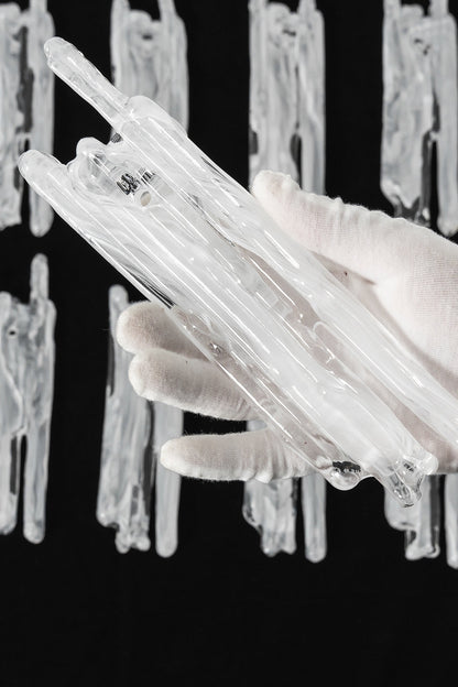 Ethereal Icicle Waterfall Chandelier | Glass, Metal | A gloved hand inspecting a single organic hand-blown glass panel to demonstrate its textured icicle design | Scale reference shot | vexa lamps